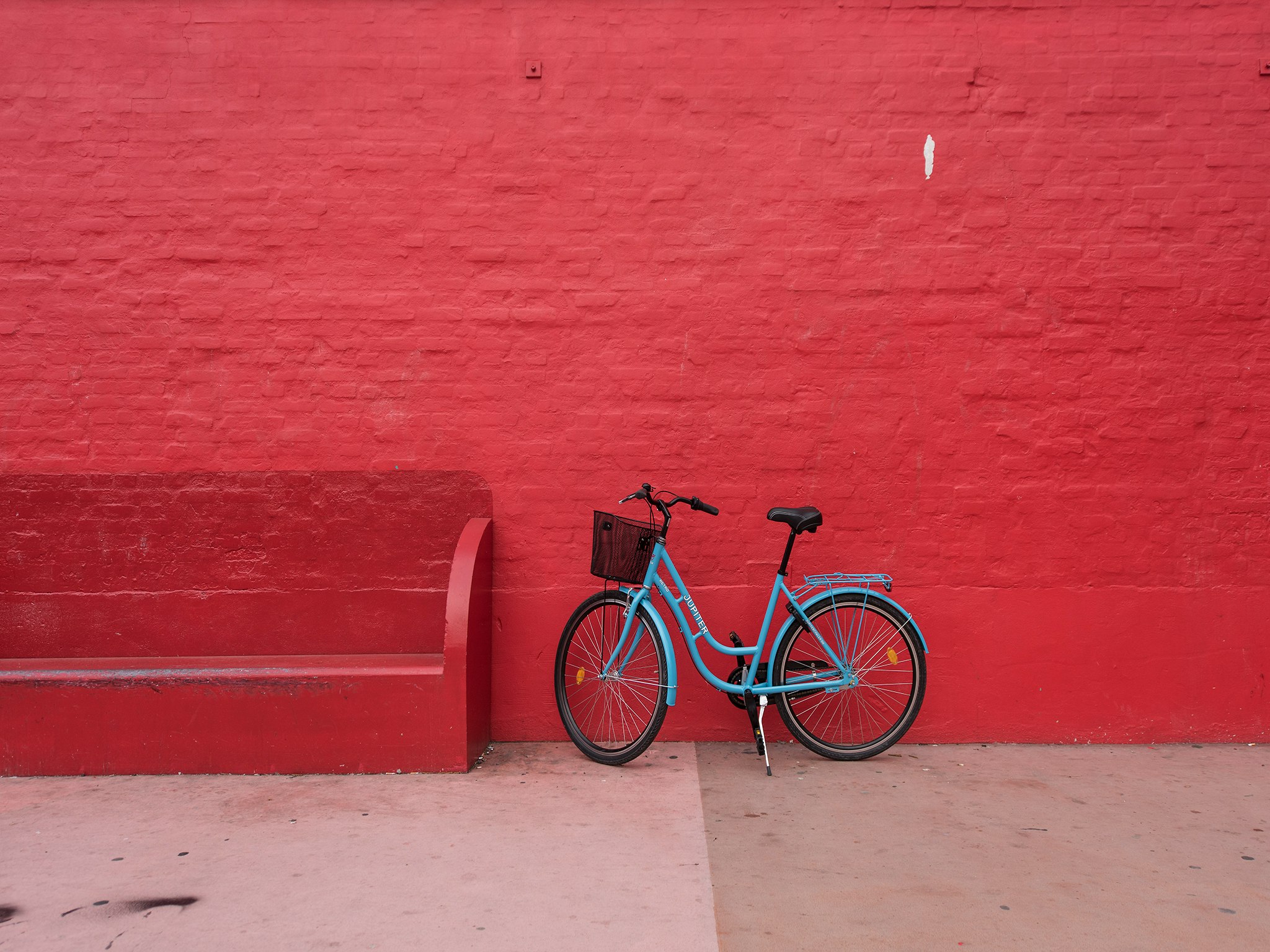 blue step-through bicycle park beside of red bench